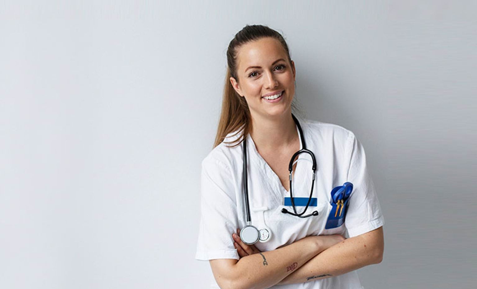 Healthcare worker smiling, wearing scrubs and stethoscope