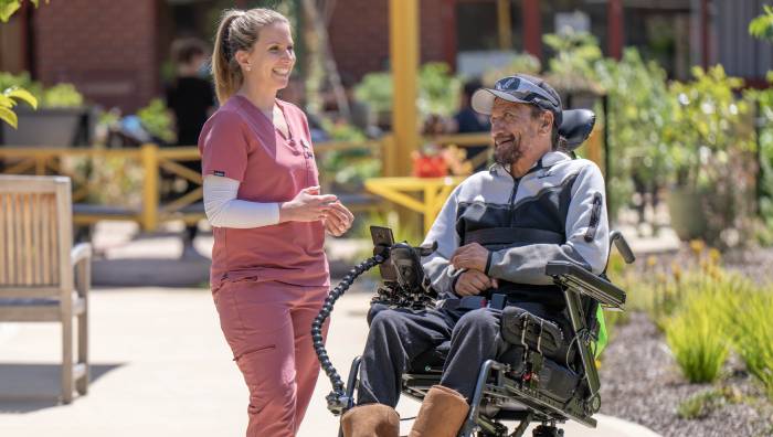 Image of a nurse having a chat with person on a wheelchair.