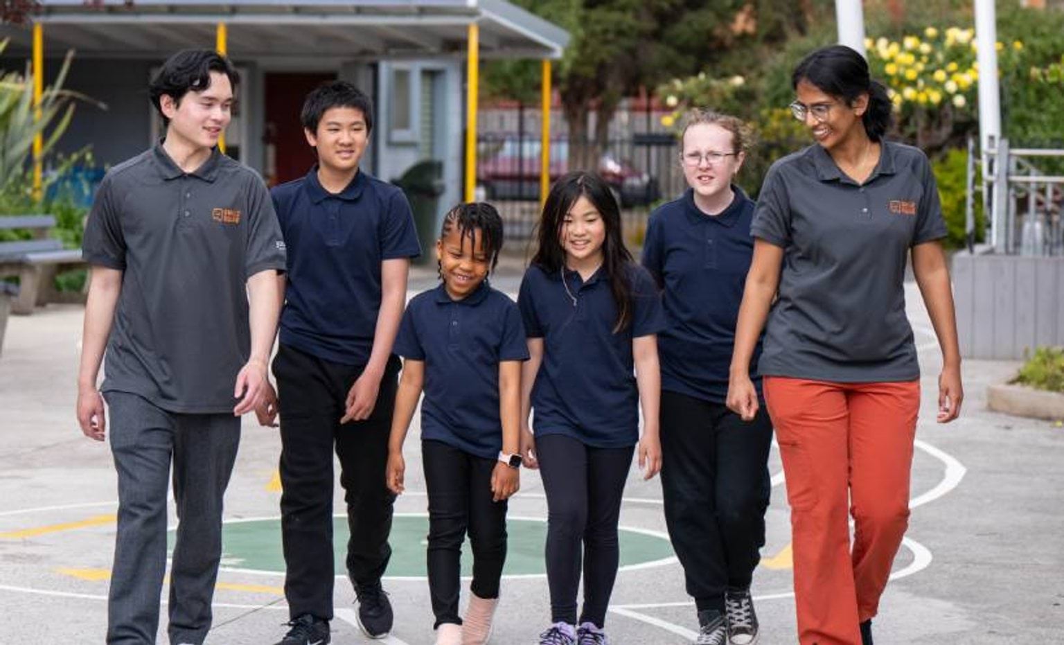 A group of students walk in the school yard with Smile Squad staff