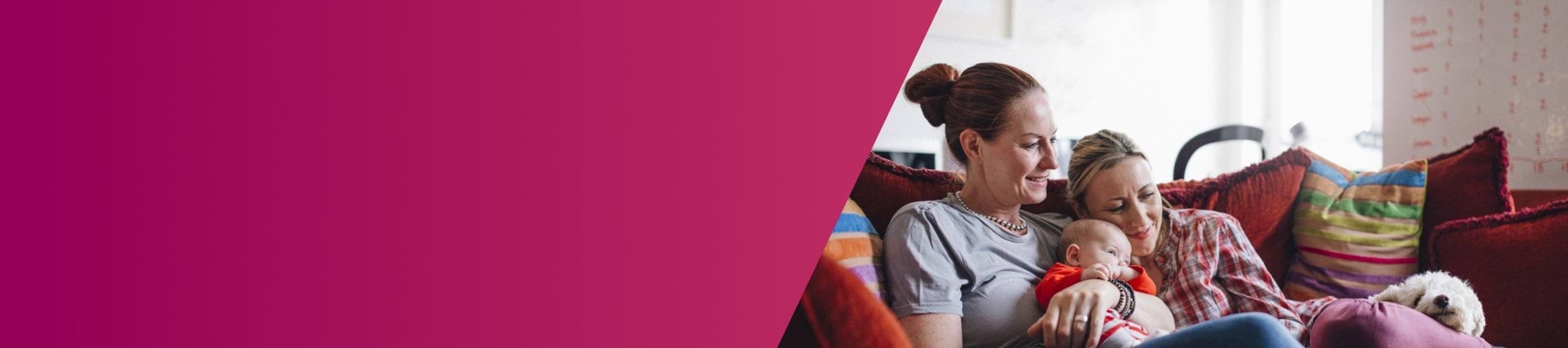 two women holding a baby on the couch next to a small white dog