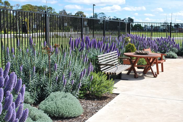 A walkway and garden with a bench and table in a dementia-friendly environment